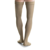 man wearing jobst formen thigh high compression sock closed toe in tan khaki, back view