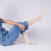 model posing with medi rejuva compression sock knee high in heart multicolor, wearing a blue denim overall