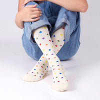 model posing with medi rejuva compression sock knee high in heart multicolor, wearing a blue denim overall