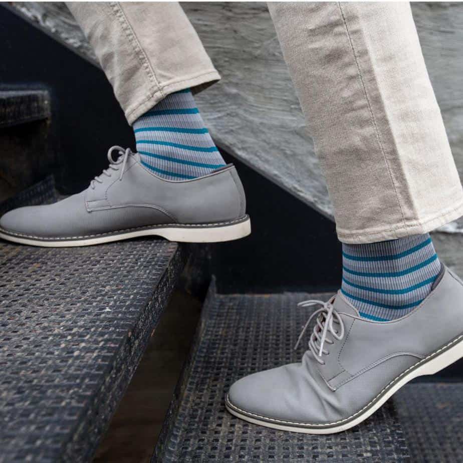 model wearing medi rejuva high knee compression sock in stripe grey teal, walking up an outdoor stair