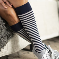 women lying on the couch wearing the sigvaris microfibre compression sock in mariner stripe colour