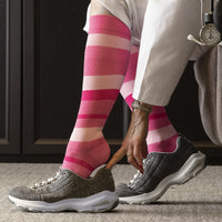 nurse sitting on a chair putting on the sigvaris microfibre pattern compression sock in pink stripe