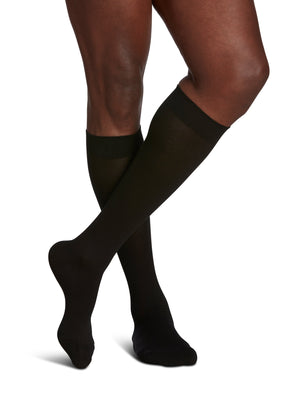 man sitting on bar stool wearing black sigvaris sea island compression sock