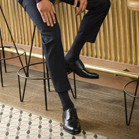 woman sitting on work chair waering black sigvaris sea island compression sock in grey trouser