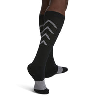 close-up of leg wearing black sigvaris athletic recovery compression sock, back view