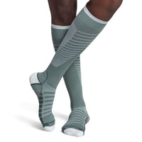 model wearing sigvaris flow tech compression sock in sage, front view.