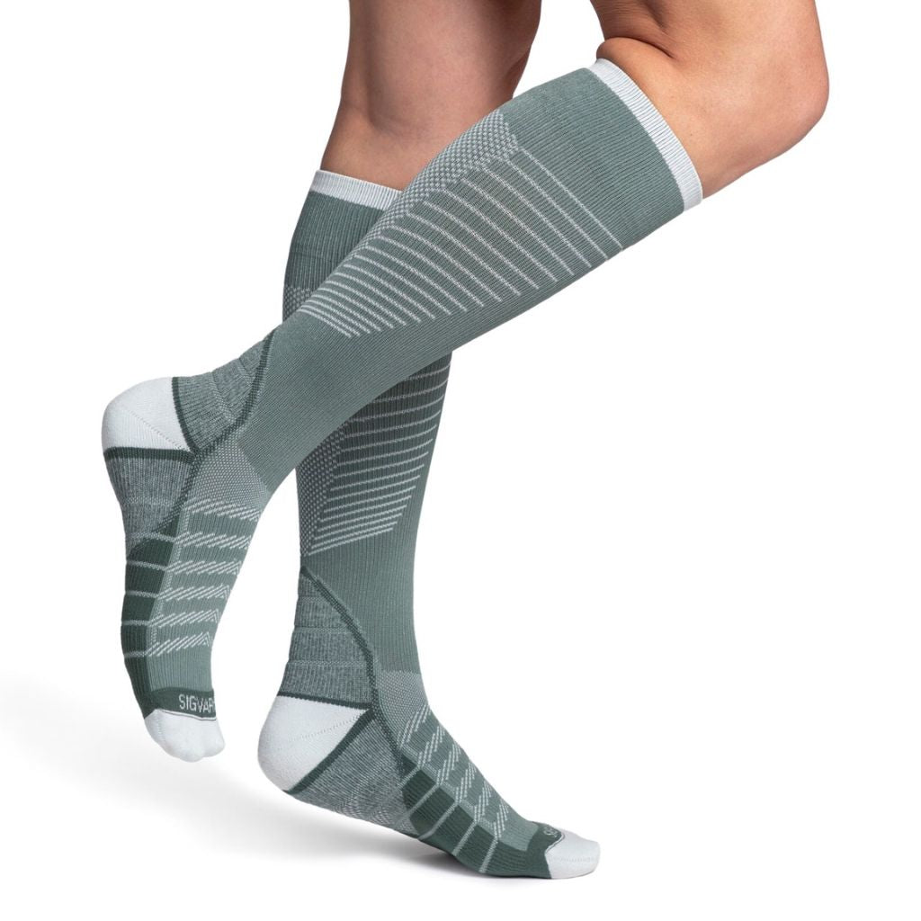model wearing sigvaris flow tech compression sock in sage, side view.