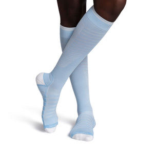model wearing sigvaris flow tech compression sock in sky blue, front view.