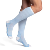 model wearing sigvaris flow tech compression sock in sky blue, side view.