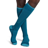 model wearing sigvaris flow tech compression sock in teal, front view.