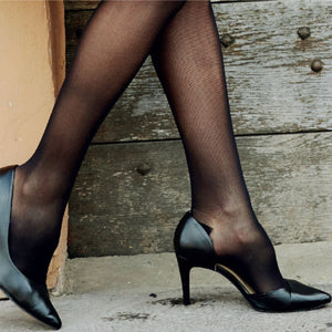 woman is standing wearing sigvaris black knee high compression socks