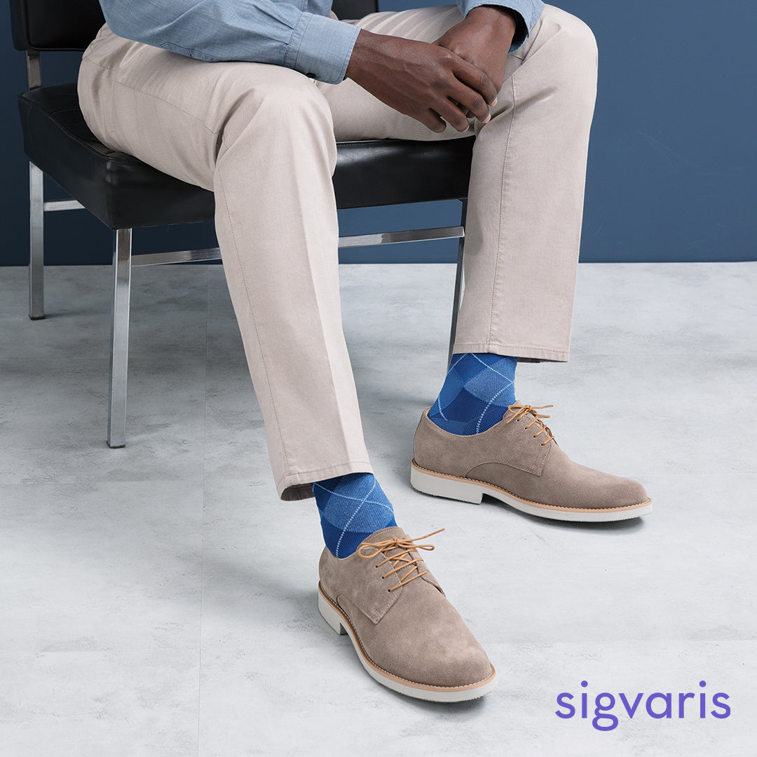 men sitting on a chair posing with the sigvaris microfibre patterns socks in royal blue argyle colour