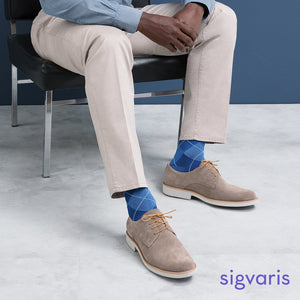 men sitting on a chair posing with the sigvaris microfibre patterns socks in royal blue argyle colour