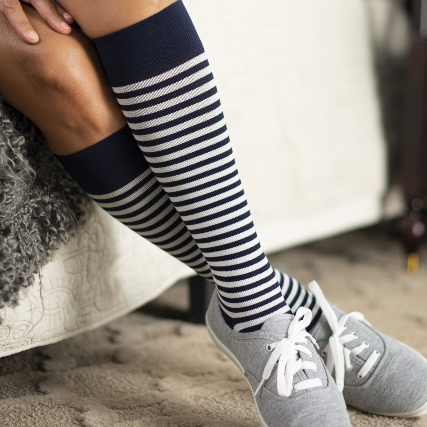 women lying on the couch wearing the sigvaris microfibre compression sock in mariner stripe colour
