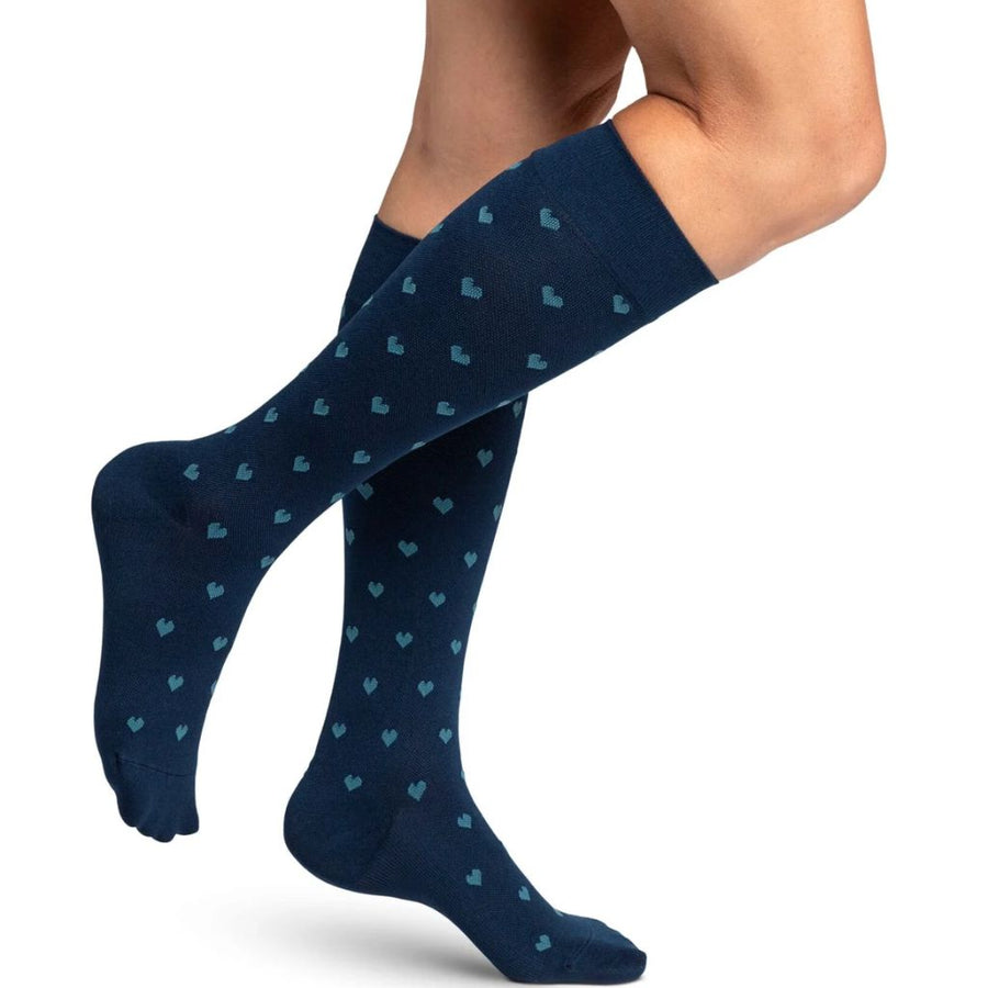 woman model wearing sigvaris microfibre pattern compression sock in navy hearts, side view.