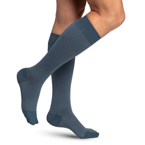 woman model wearing sigvaris microfibre pattern compression sock in storm blue conffeti, side view.