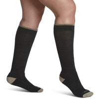 close-up of a leg wearing sigvaris merino wool outdoor compression sock in charcoal colour, side view.